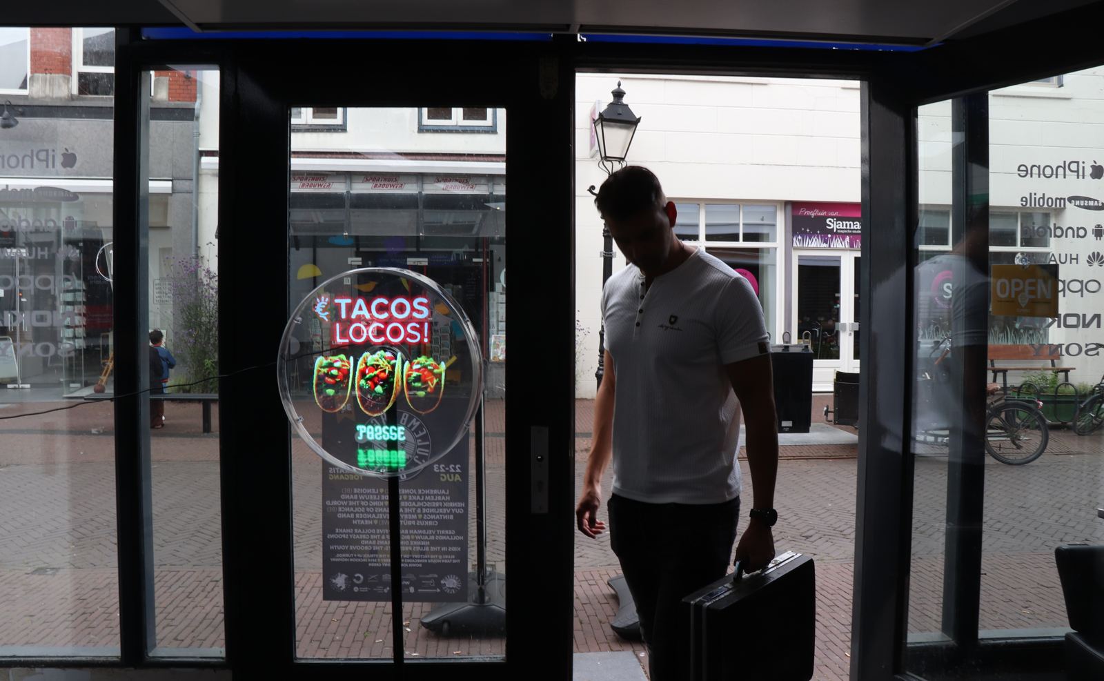 Hologram met Tacos Locos achter de glazen deur van een winkel, gezien vanaf binnen